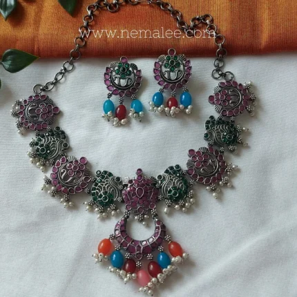 Ruby and green stone studded intricate silver look alike necklace with earrings
